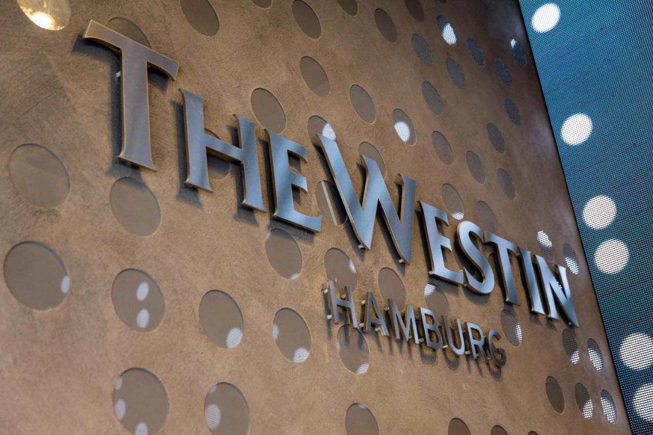 The Westin Hamburg Elbphilharmonie Hotel Ngoại thất bức ảnh The image shows a decorative wall featuring the logo of "The Westin Hamburg." The logo is prominently displayed in a sleek, silver font. The background has a textured surface with circular patterns, adding a modern and elegant touch to the overall ap