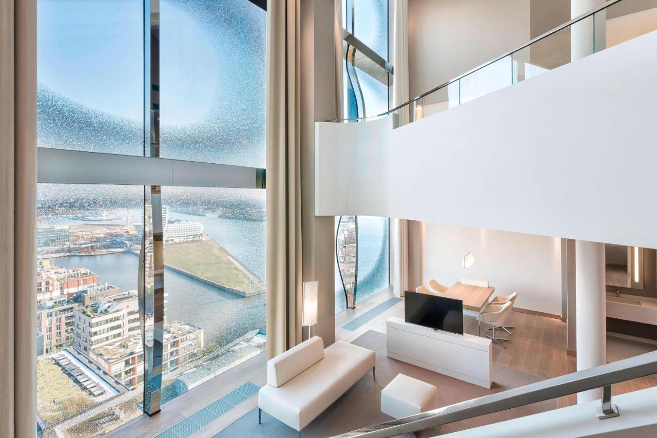 The Westin Hamburg Elbphilharmonie Hotel Ngoại thất bức ảnh The photo showcases a modern, stylish interior of a multi-level living space. It features large, floor-to-ceiling windows that provide a panoramic view of the surrounding landscape and water. The decor is minimalist, with a predominantly white color 